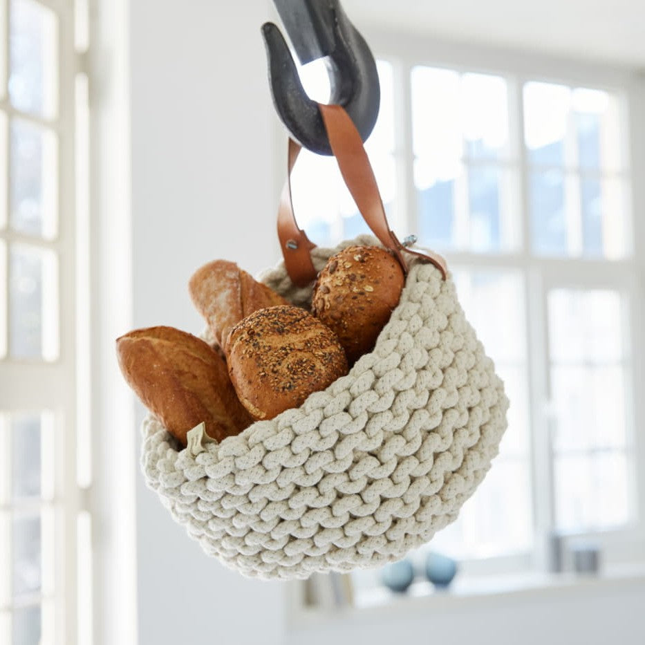 flechtkorb als brotkorb mit brot befüllt hängend an einem Haken