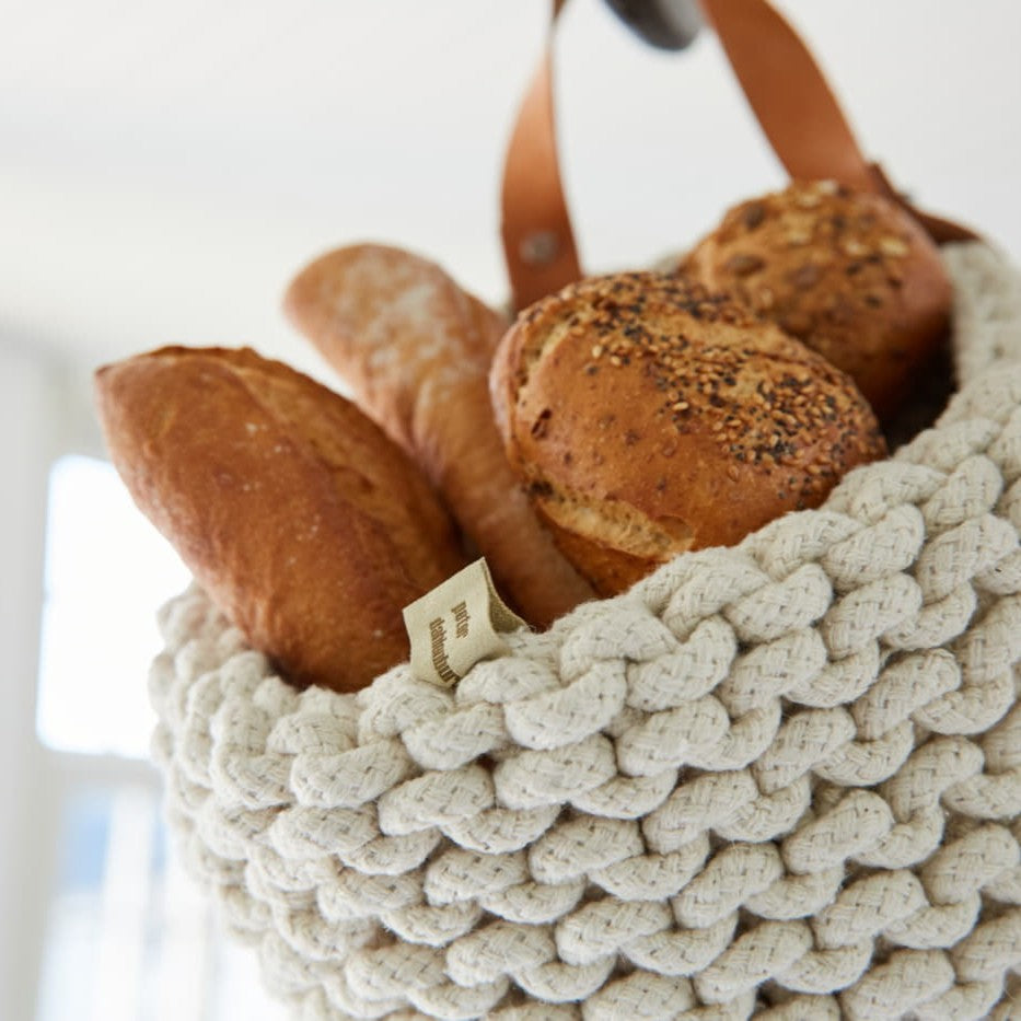 Nahaufnahme flechtkorb als brotkorb mit brot befüllt hängend an einem Haken