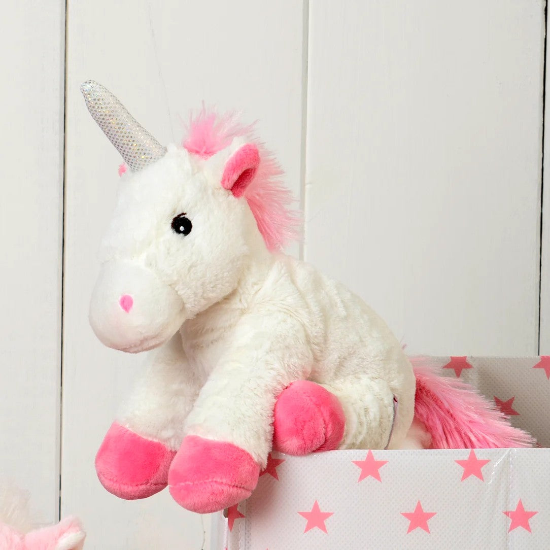 Warmies Einhorn sitzend in einer weißen Spielzeugkiste mit rosa Sternen